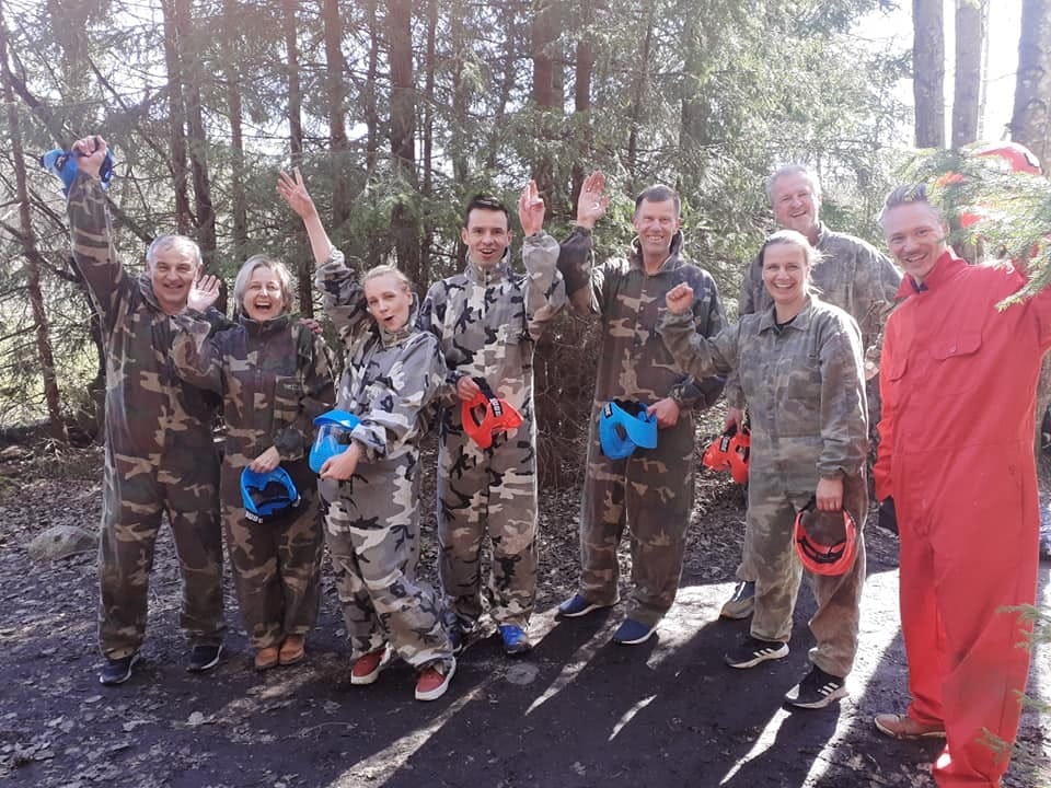 Flera personer poserar framför kameran och iklädd paintball-kläder och utrustning på skogsbana.